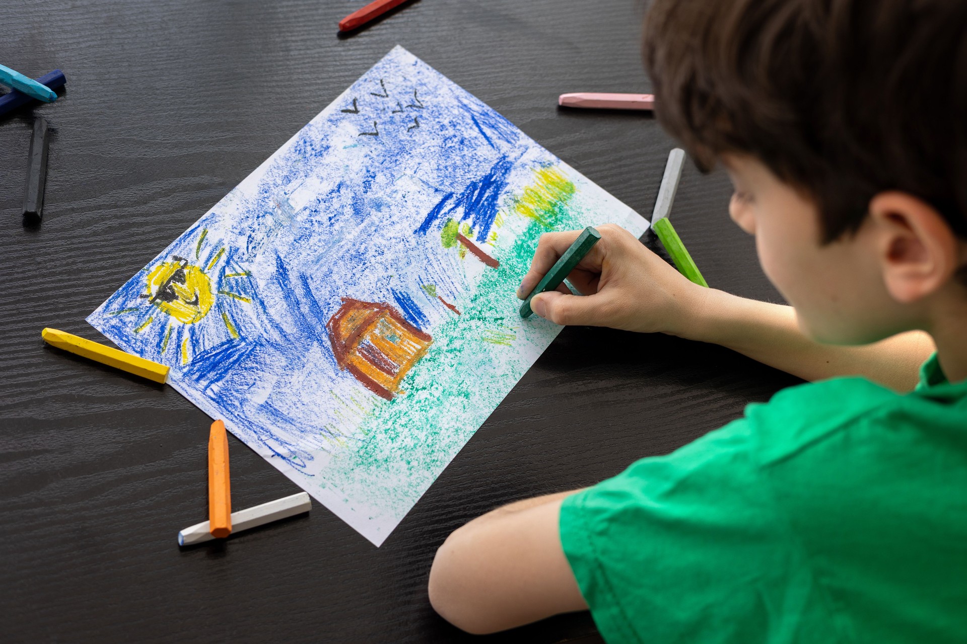 Focused Child in Green T-shirt Drawing with Crayons - Art Therapy for Autism, ADHD, and Digital Detox Concept. boy drawing with colorful pastels